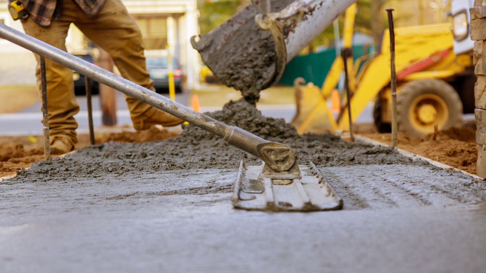 Construction worker smoothing wet concrete with trowel at job site