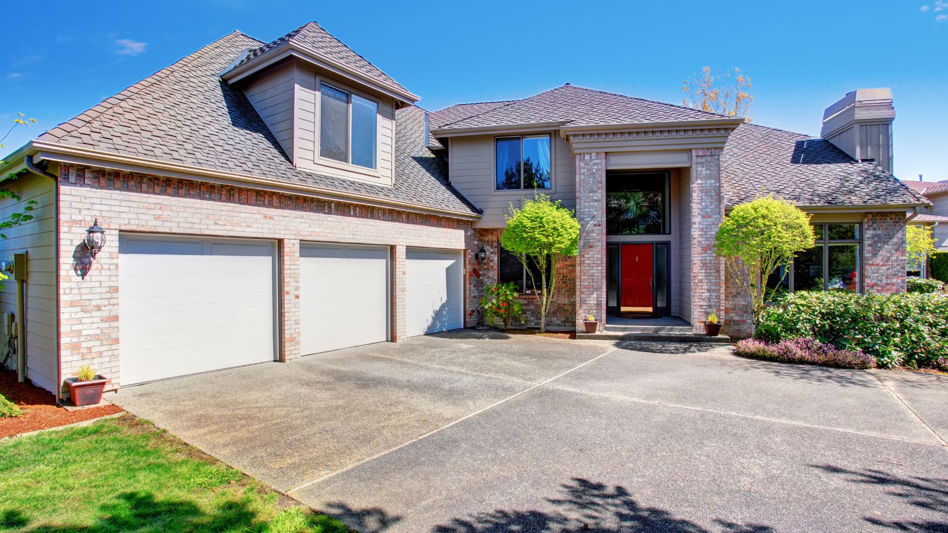 Suburban two-story brick house with three-car garage and red front door