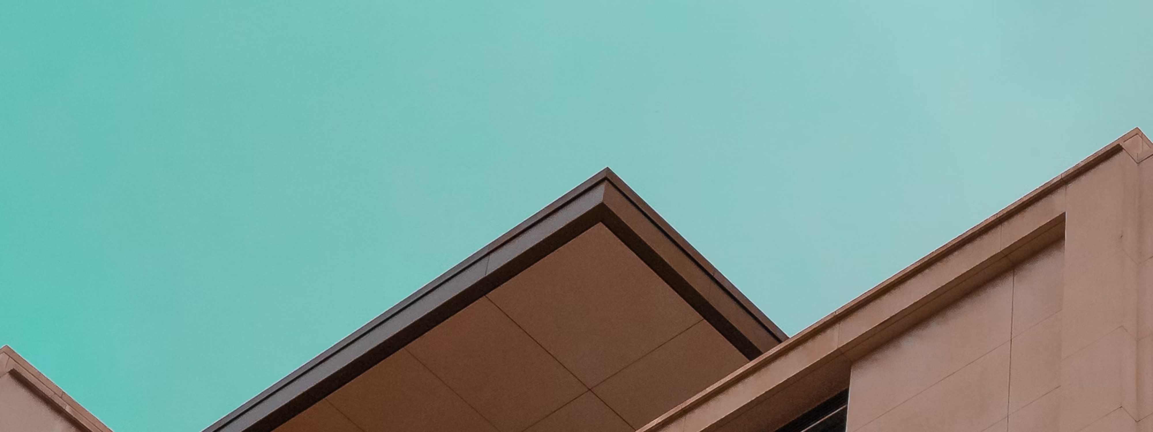 Modern architectural rooflines against turquoise sky, geometric shapes